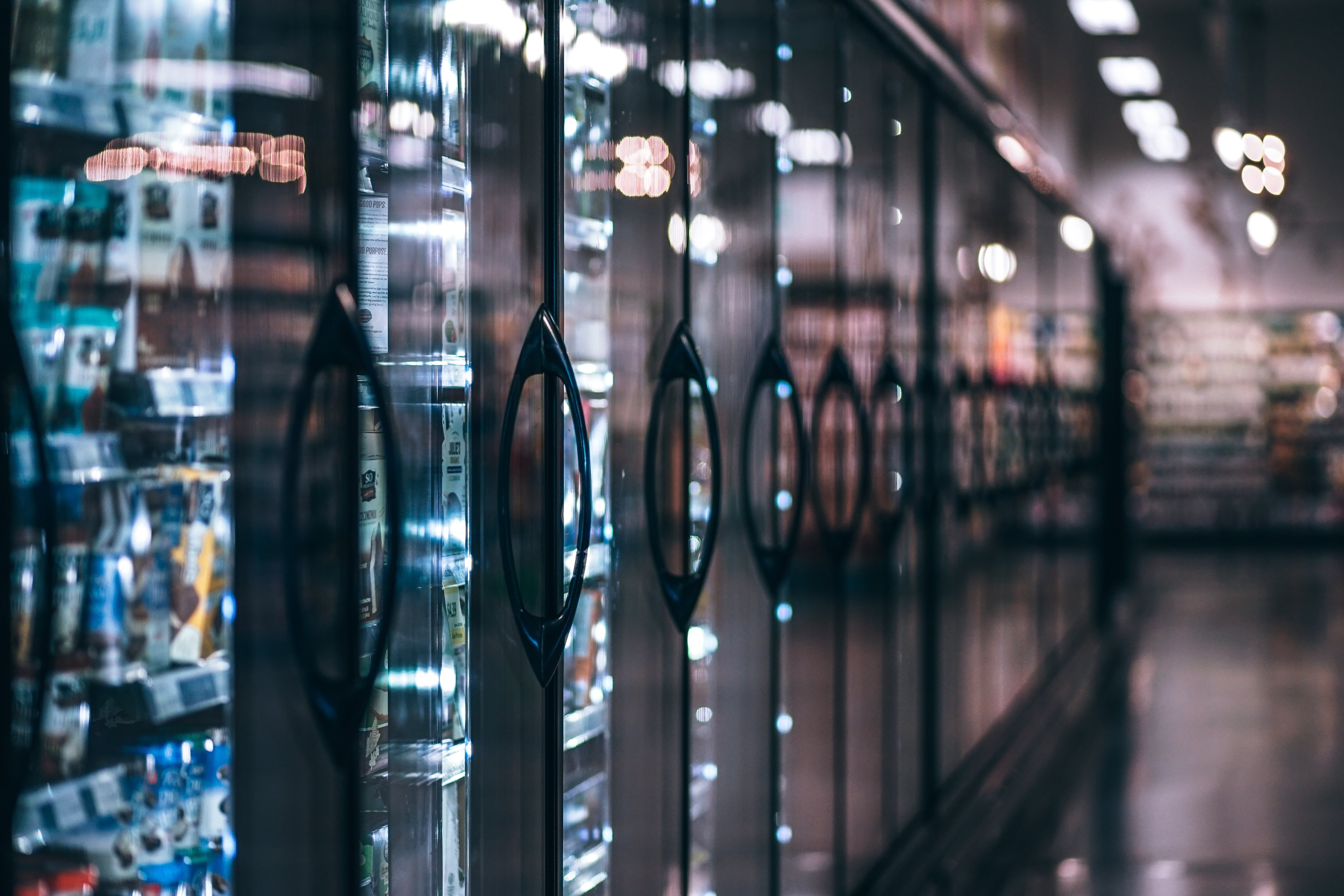 A row of commercial refrigerators in a well-lit supermarket aisle